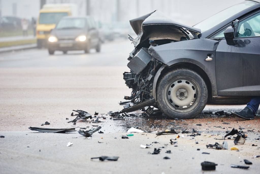 Car crash on busy road front collision road debris daytime oncoming vehicles in background