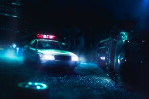 Police car arriving at crash scene at night car overturned debris on road