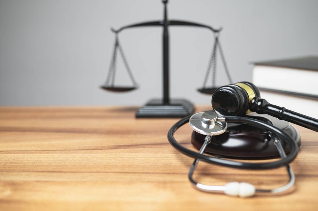 Gavel stethoscope and justice scales on pine wood table personal injury law 
